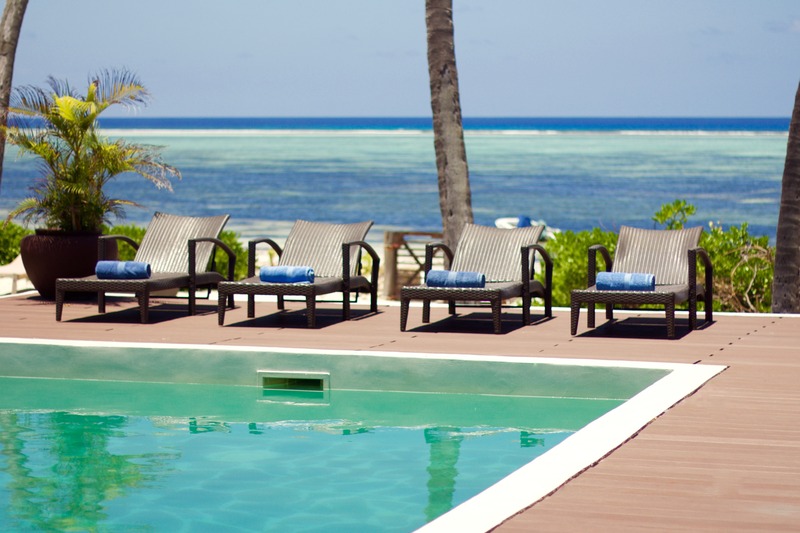 The pool at Villa Turquoise, loungers along it and the reef beyond